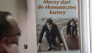 Na zdjęciu mężczyzna patrzący na baner z napisem mocny start do kariery ekonomicznej