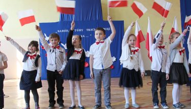 Dzieci machają bialo-czergonymi flagami