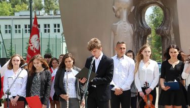 Młodzież stoi przed pomnikiem Pękniętego Serca Matki w Łodzi