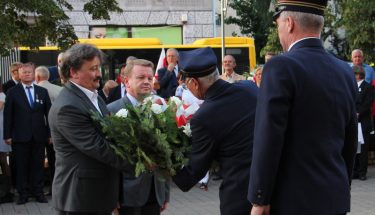 Kurator i wicekurator podają strażnikom miejskim kwiaty, które mają być złożone przed pomnikiem