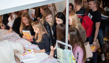 Zdjęcie grupy uczniów zgromadzonych przy jednym ze stoisk podczas Łódzkiego Salonu Maturzystów 2019