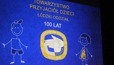 Zdjęcie z jubileuszu stulecia Towarzystwa Przyjaciół Dzieci, widać na nim plansze z logiem organizacji i informacja o jubileuszu