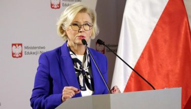 Wiceminister Marzena Machałek stoi przed mównicą podczas konferencji, za nią stoi baner z napisem Ministerstwo Edukacji i Nauki oraz flagi Polski