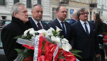 Wicepremier Piotr Gliński składa kwiaty pod tablica pamiątkową na budynku Kuratorium Oświaty w Łodzi. Na zdjęciu także kurator i wicekurator oświaty