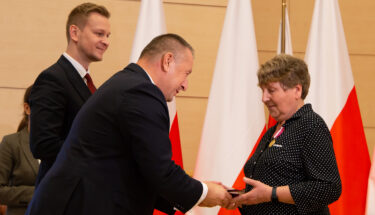 Kurator oświaty gratuluje osobie odznaczonej Medalem za Długoletnią Służbę