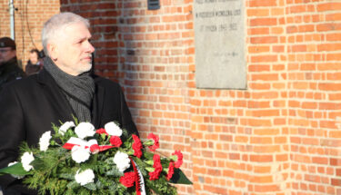 Zdjęcie przedstawiające Łódzkiego Kuratora Oświaty z wiązanką biało-czerwonych kwiatów